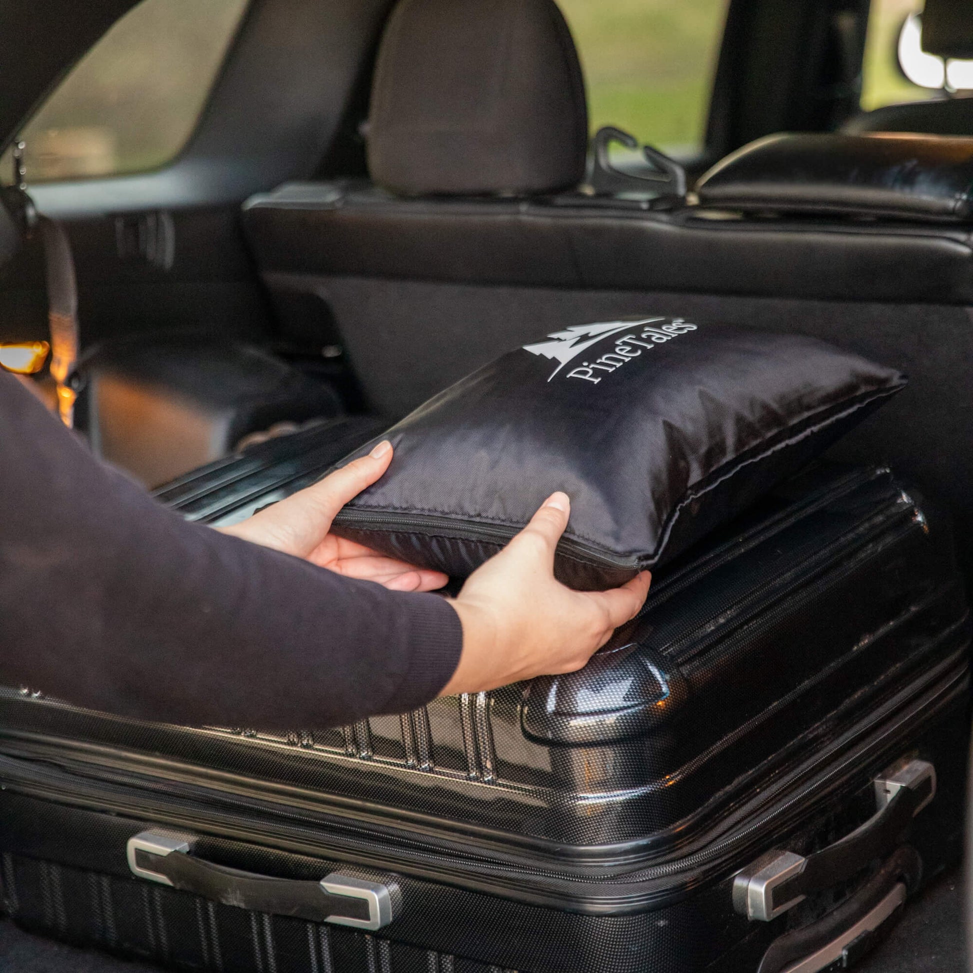 Buckwheat Travel Pillow being put into a cars trunk alongside other luggage