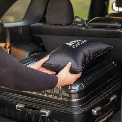 Buckwheat Travel Pillow being put into a cars trunk alongside other luggage